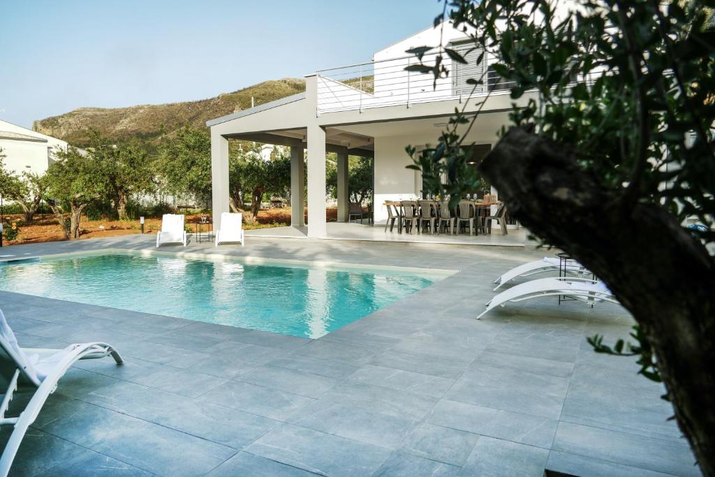 une piscine avec des chaises et une maison dans l'établissement Luxury Villa La Perla - Castellammare del golfo with Pool, Garden and Parking, à Castellammare del Golfo