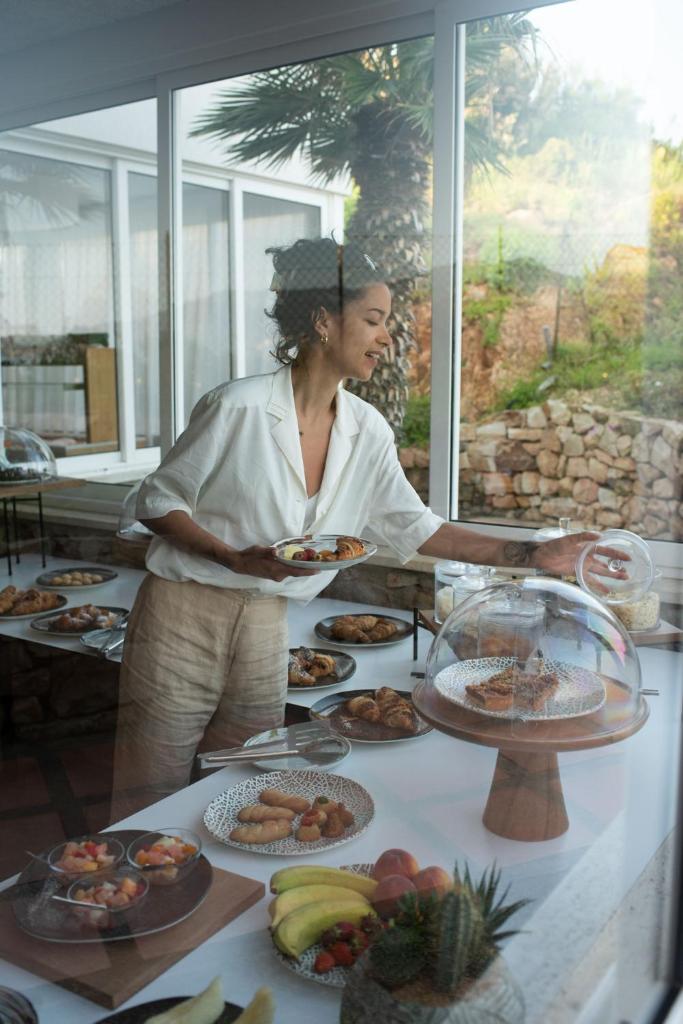une femme tenant une assiette de nourriture sur une table dans l'établissement MClub Cala Regina, à Sciacca