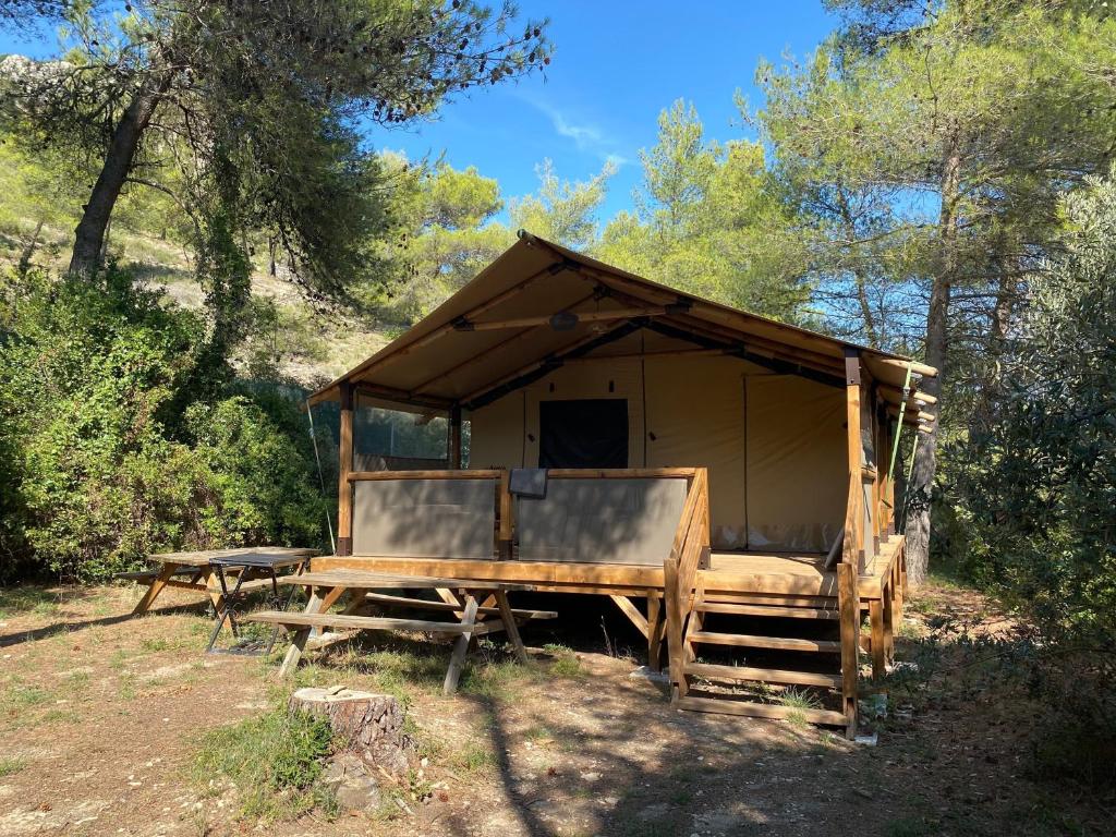 une tente en bois avec une table dans une forêt dans l'établissement Camping maeva Respire La Vallée Heureuse, à Orgon