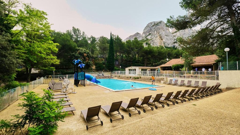 - une piscine avec des chaises et un toboggan dans l'établissement Camping maeva Respire La Vallée Heureuse, à Orgon