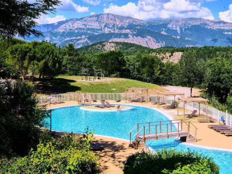 une grande piscine avec des montagnes en arrière-plan dans l'établissement Camping maeva Escapades Le Couriou, à Recoubeau-Jansac
