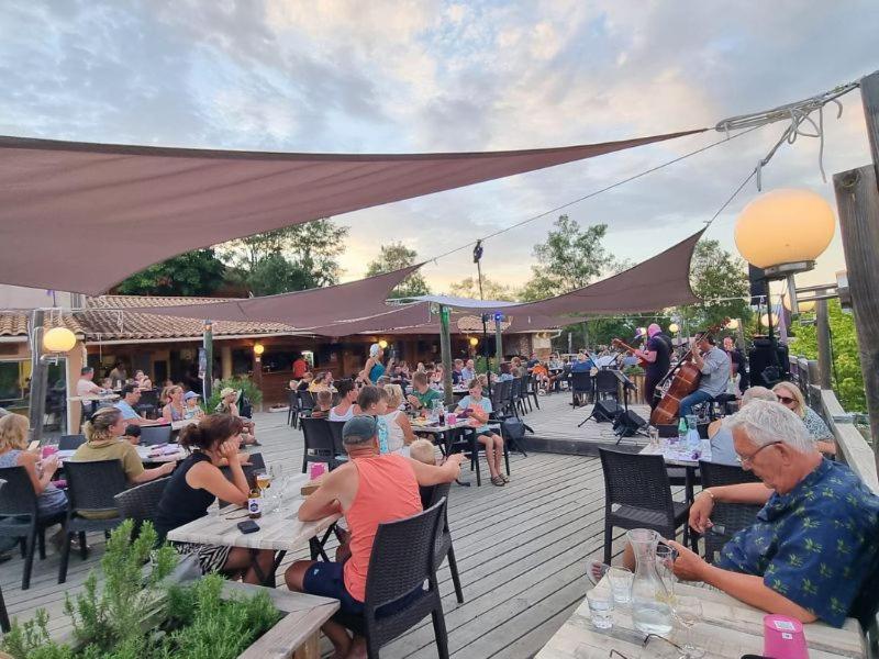 un groupe de personnes assises à des tables sur un patio dans l'établissement Camping maeva Escapades Le Couriou, à Recoubeau-Jansac