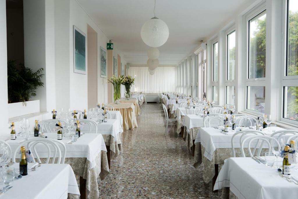 une rangée de tables dans une pièce avec des nappes blanches dans l'établissement Grande Albergo Marin, à Lignano Sabbiadoro