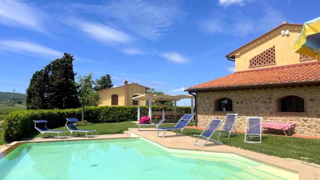 une piscine avec des chaises et une maison dans l'établissement Villa Marina with private panoramic pool - Borgo del Silenzio, à Orciatico