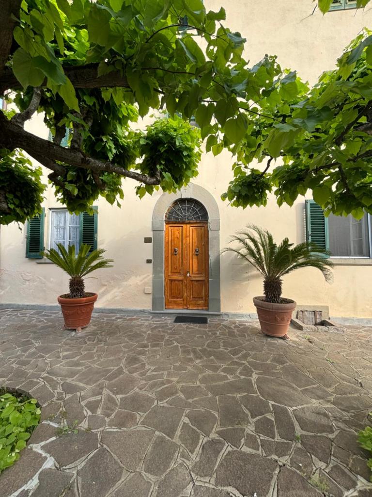 un bâtiment avec une porte en bois et deux plantes en pot dans l'établissement Agriturismo Fuccioli II, à Carmignano