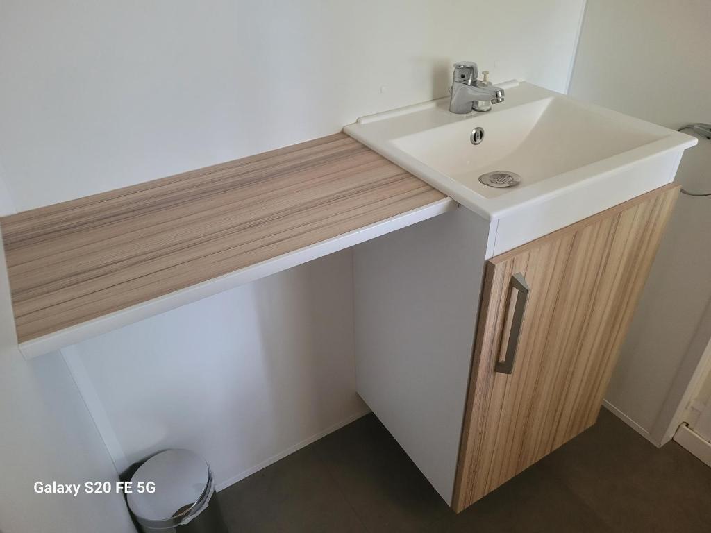 La salle de bains est pourvue d'un lavabo blanc et d'un comptoir en bois. dans l'établissement MOBIL HOME 4 à 6 PERS Le Canet en Roussillon, à Canet
