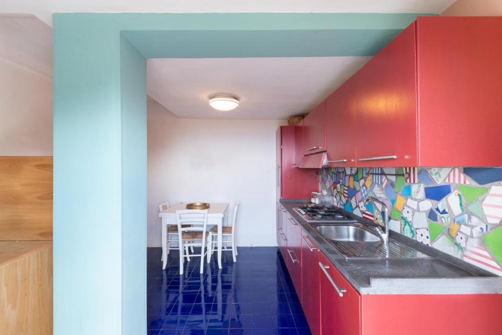 une cuisine avec des armoires rouges et une table avec des chaises dans l'établissement Casa Tiberius Capri Retreat, à Capri 32 autres photos