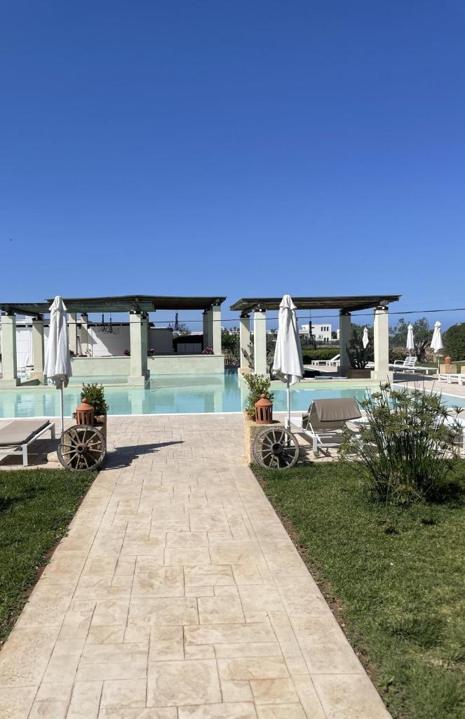 une passerelle à côté d'une piscine avec des parasols dans l'établissement Villa Elisabetta con idromassaggio e area piscina, à Gallipoli