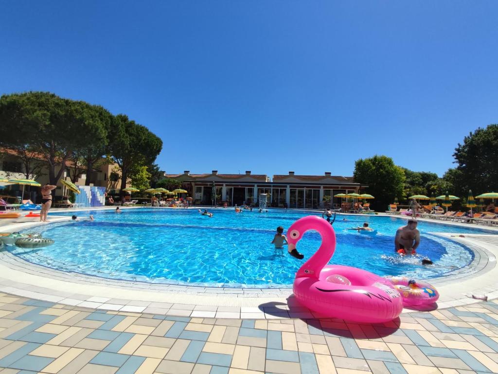 une piscine avec un cygne rose au milieu dans l'établissement Villaggio Marco Polo, à Bibione