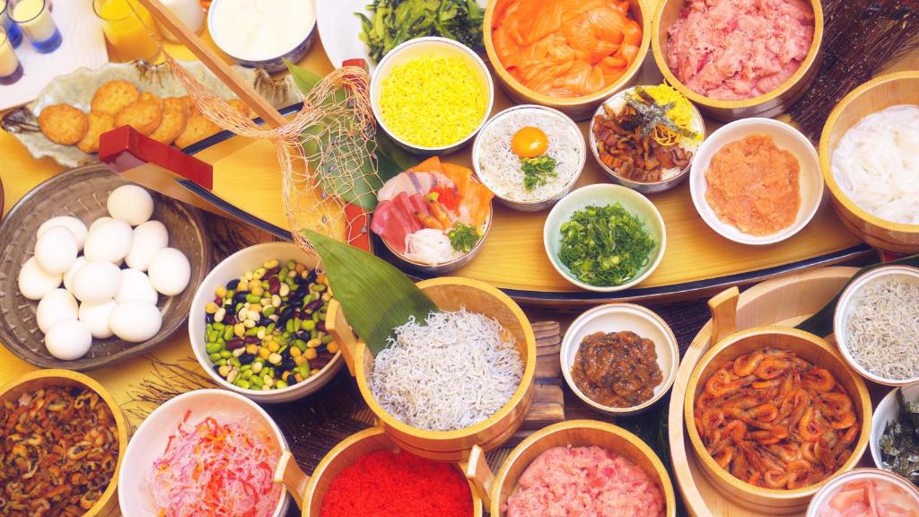 une table avec de nombreux types de denrées alimentaires dans des bols dans l'établissement The Gran Resort Elegante Awajishima, à Awaji