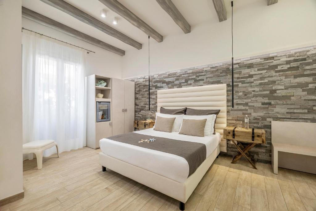 une chambre avec un grand lit et un mur de briques dans l'établissement Hotel Soffio D'Estate, à San Vito Lo Capo 43 autres photos