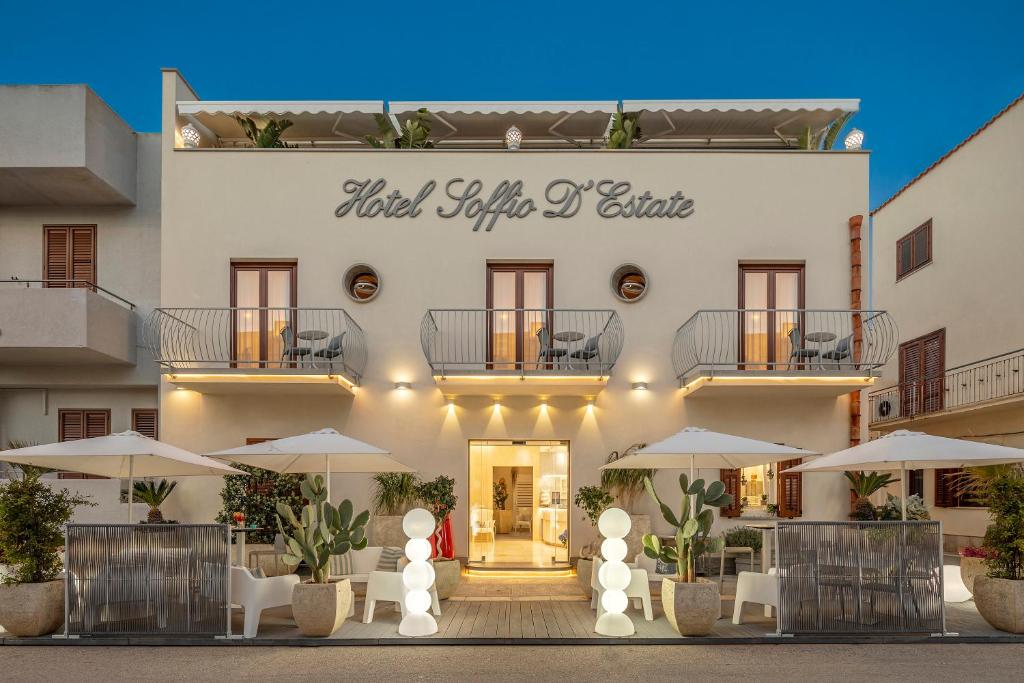 un hôtel avec des tables et des parasols devant un bâtiment dans l'établissement Hotel Soffio D'Estate, à San Vito Lo Capo