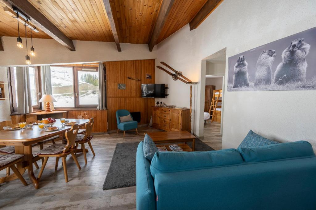 un salon avec un canapé bleu et une table dans l'établissement Echo des marmottes - Au pied des pistes - Parking, à Enchastrayes