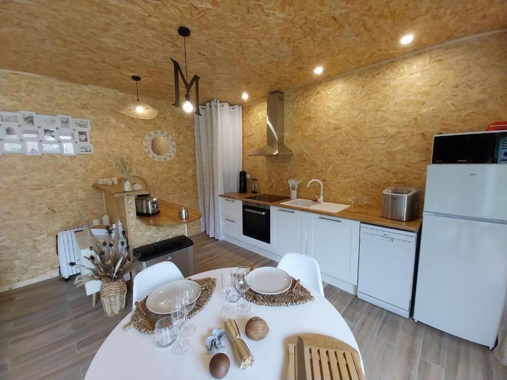 une cuisine avec une table et un réfrigérateur blanc dans l'établissement Le Clos FMR Insolite Manon Carcassonne, à Malves 34 autres photos