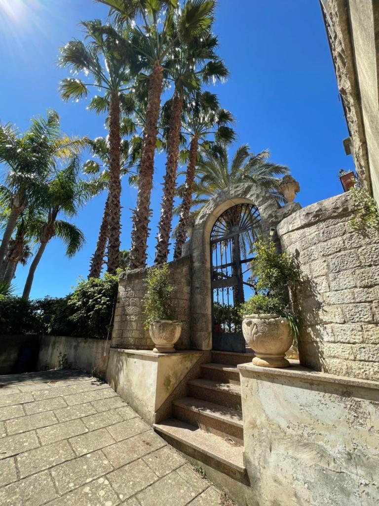 un mur de pierre avec des palmiers et des escaliers avec des palmiers dans l'établissement ALTA lux homeholiday stone, à Modica