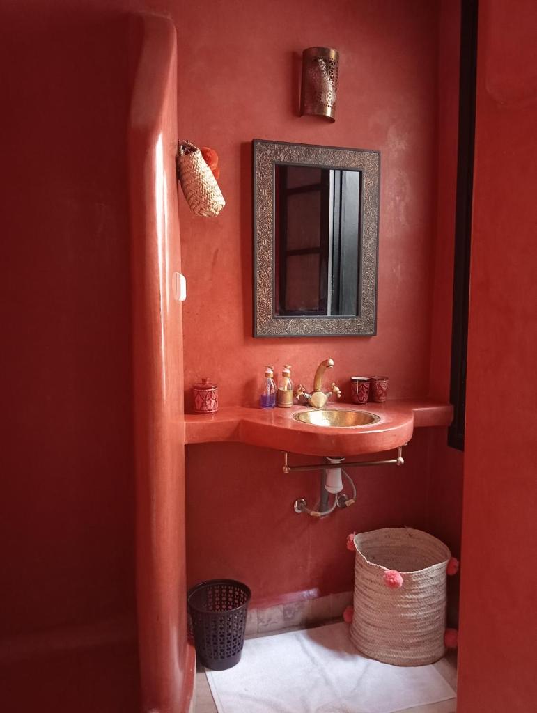 La salle de bains rouge est pourvue d'un lavabo et d'un miroir. dans l'établissement Le riad de l'étoile ocre - COTG, à Marrakech