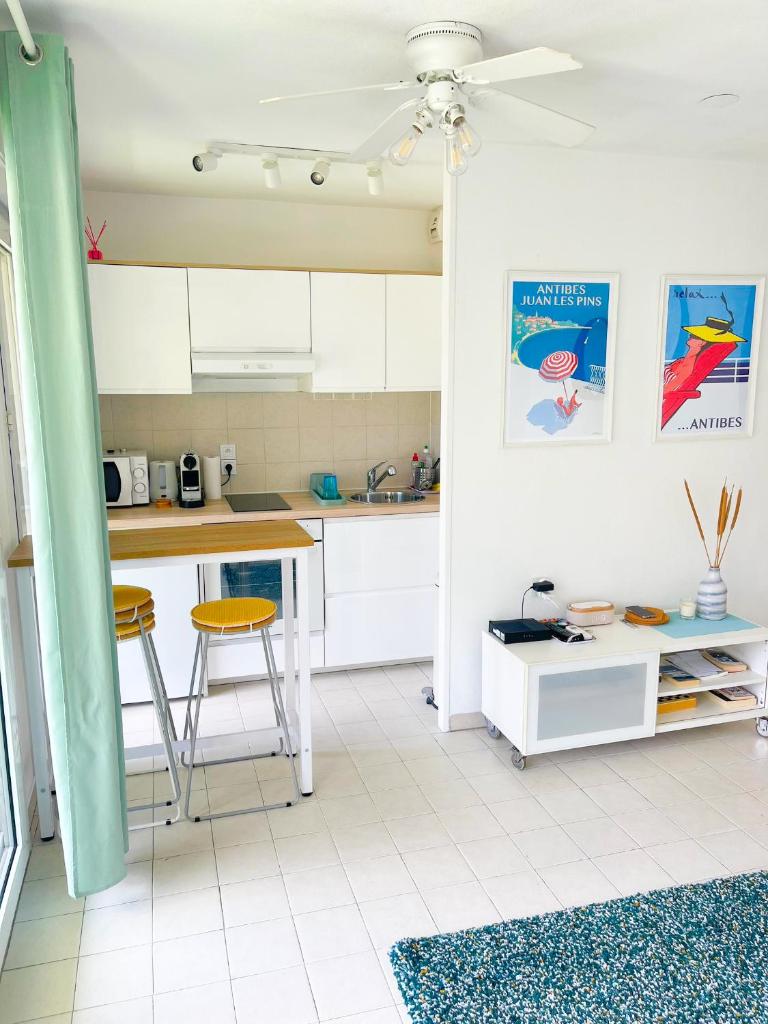 une cuisine avec des placards blancs, une table et des tabourets dans l'établissement 1 bedroom Sea view, swimming pool, beach on foot, parking, à Antibes 12 autres photos
