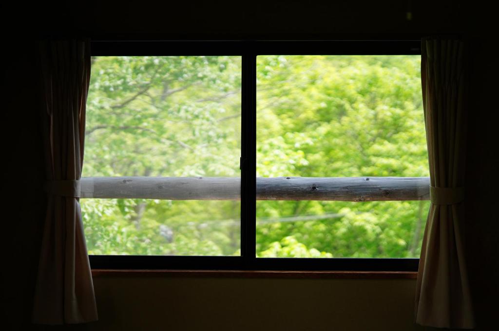une fenêtre avec vue sur un arbre dans l'établissement ピーポロ乗鞍, à Matsumoto