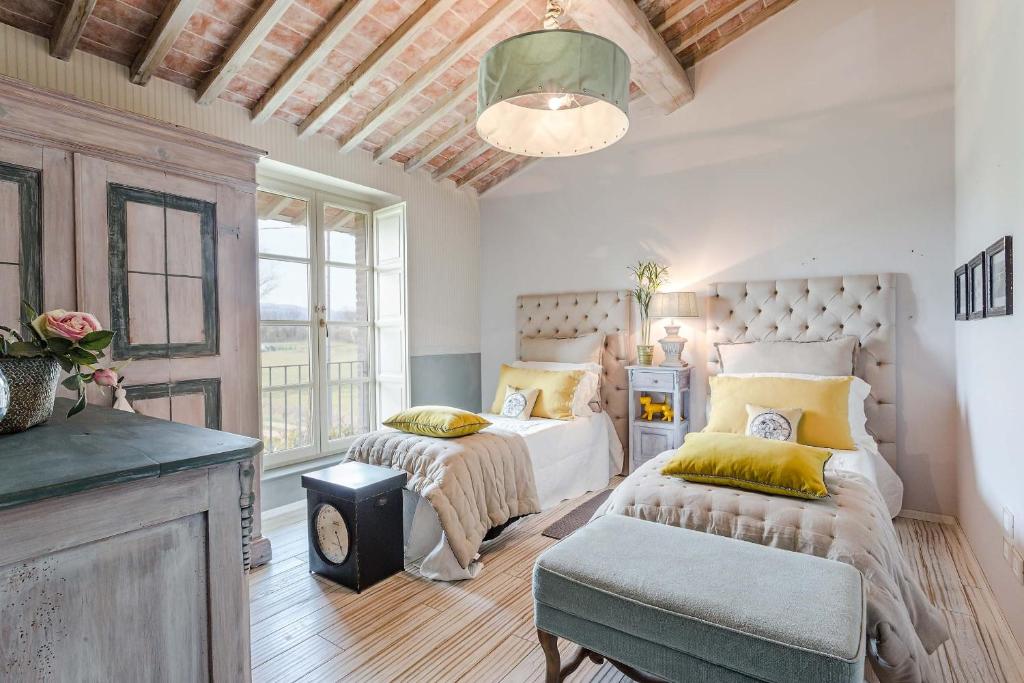 une chambre avec deux lits et un banc dans une pièce dans l'établissement Villa Otto Luxury Tuscan Farmhouse with Pool, à Orentano