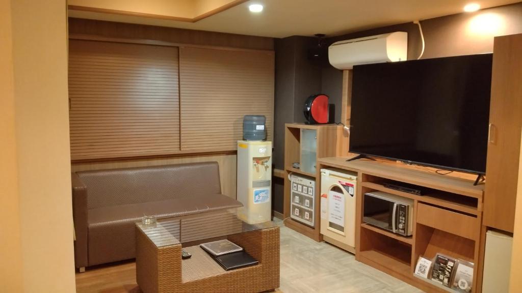 - un salon avec une grande télévision et un canapé dans l'établissement agehA - Adult Only-, à Fukuyama