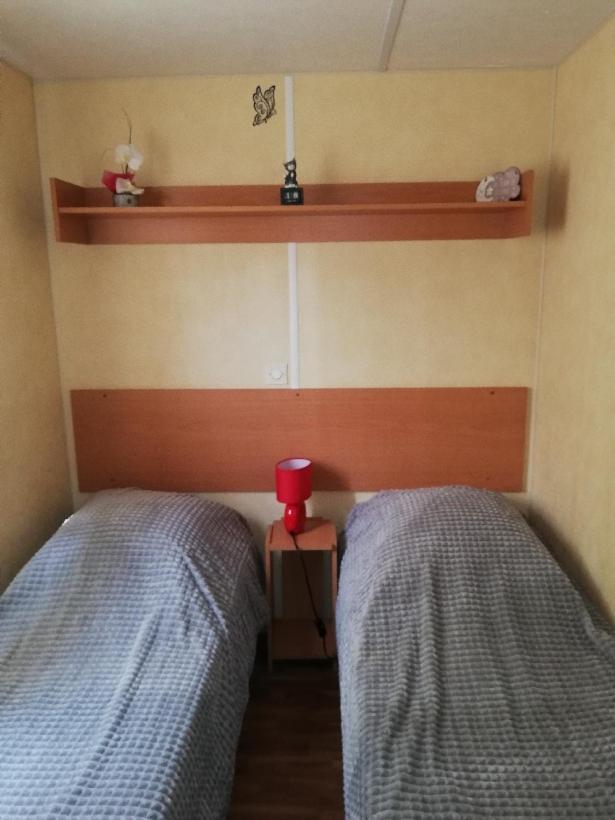 une chambre avec deux lits et une tasse rouge entre eux dans l'établissement GORGES DU VERDON CAMPING 3 etoiles PROCHE DU LAC DE STE CROIX NBRES ACTIVITES NAUTIQUES RANDONNEES ENTOURE DE CHAMPS DE LAVANDES 4 PERS, à Sainte-Croix-de-Verdon