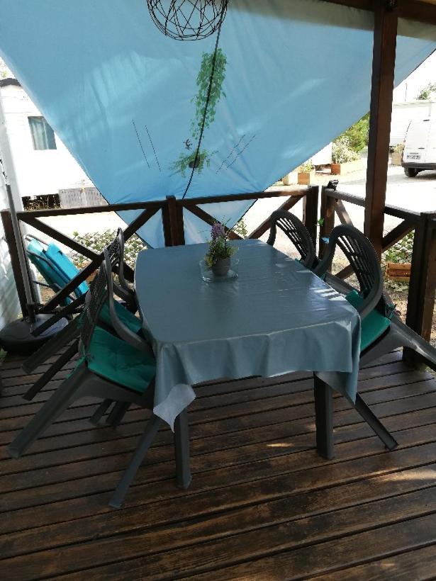 une table et une chaise sur une terrasse dans l'établissement GORGES DU VERDON CAMPING 3 etoiles PROCHE DU LAC DE STE CROIX NBRES ACTIVITES NAUTIQUES RANDONNEES ENTOURE DE CHAMPS DE LAVANDES 4 PERS, à Sainte-Croix-de-Verdon