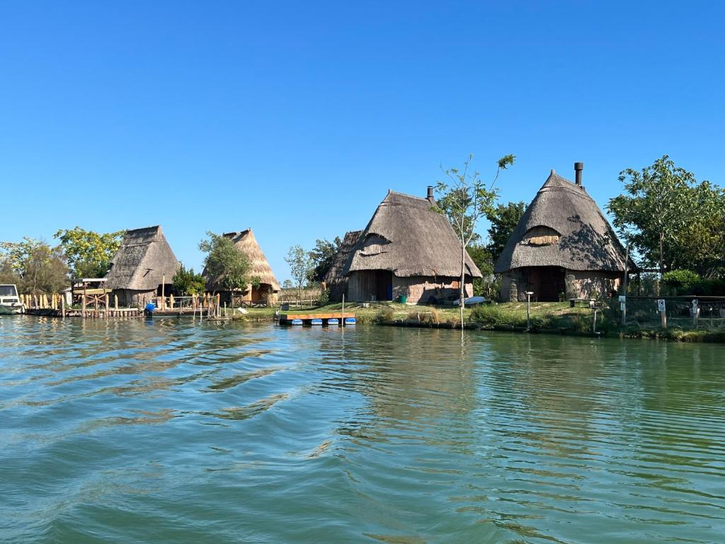 un groupe de huttes sur une île dans l'eau dans l'établissement Eco Hotel Cleofe, à Caorle