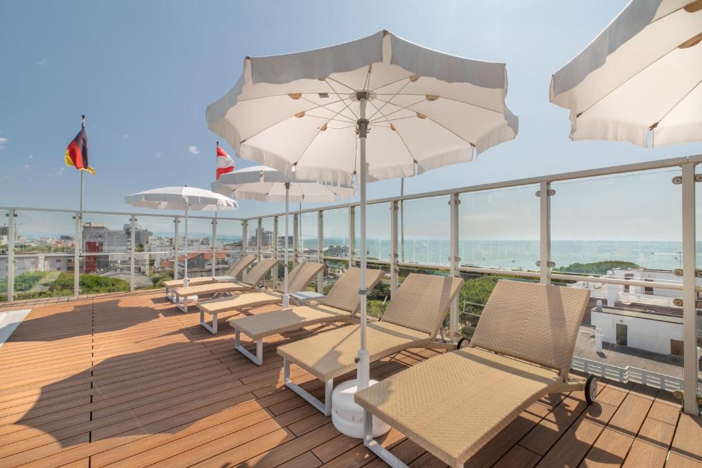 une rangée de chaises et de parasols sur une terrasse dans l'établissement Hotel Villa Doimo, à Lignano Sabbiadoro