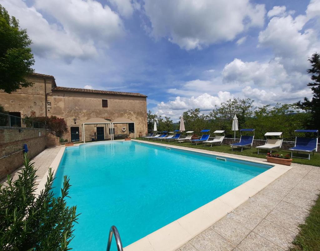 - une piscine avec des chaises longues bleues à côté d'un bâtiment dans l'établissement Pasqui Villas La Consuma villa storica in paese con vista pscina WiFi, à San Giovanni dʼAsso