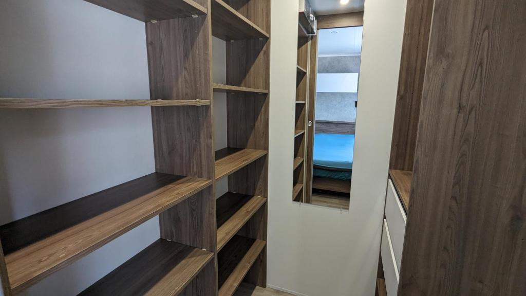 - un dressing avec des étagères en bois dans l'établissement Mobil-home 40m2 au calme, plage, piscine, forêt, à Saint-Julien-en-Born