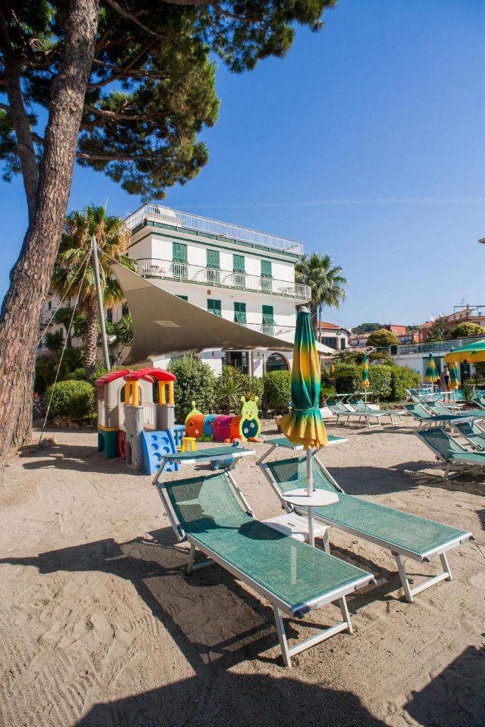 un groupe de chaises longues et un parasol sur une plage dans l'établissement Hotel Gabriella, à Diano Marina