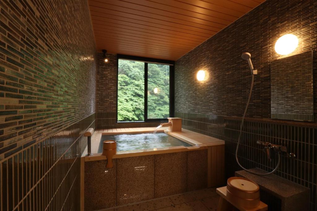 La salle de bains est pourvue d'une baignoire et d'une fenêtre. dans l'établissement Yumoto Ueyama Ryokan, à Himeji