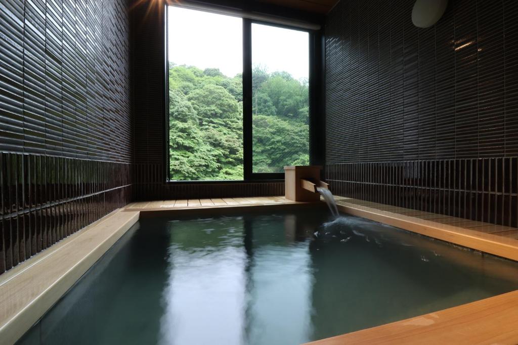 d'une salle de bains avec une piscine d'eau et une fenêtre. dans l'établissement Yumoto Ueyama Ryokan, à Himeji
