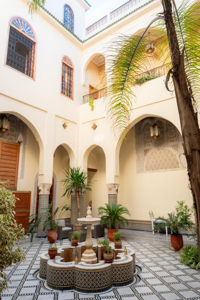une cour dans un bâtiment avec une fontaine dans l'établissement Riad Al Ansari, à Fès