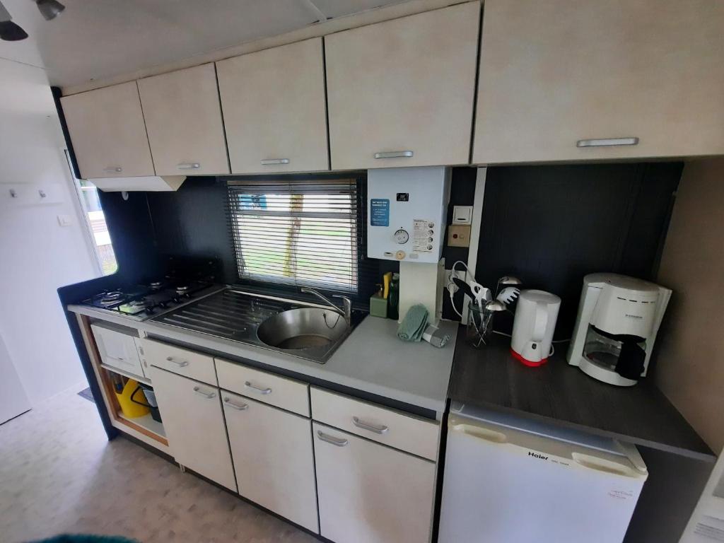 une petite cuisine avec des armoires blanches et un évier dans l'établissement Mobilhome vintage "Océane", à Tourtoirac