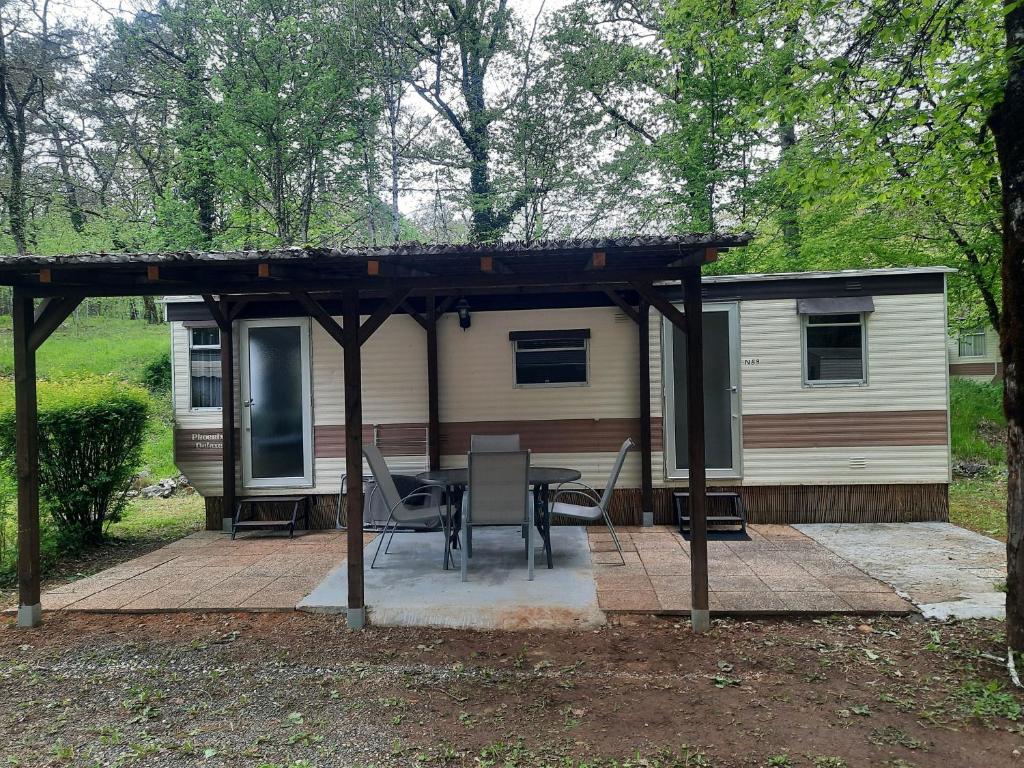 une cabane avec une table et des chaises sous un toit dans l'établissement Mobilhome vintage "Océane", à Tourtoirac