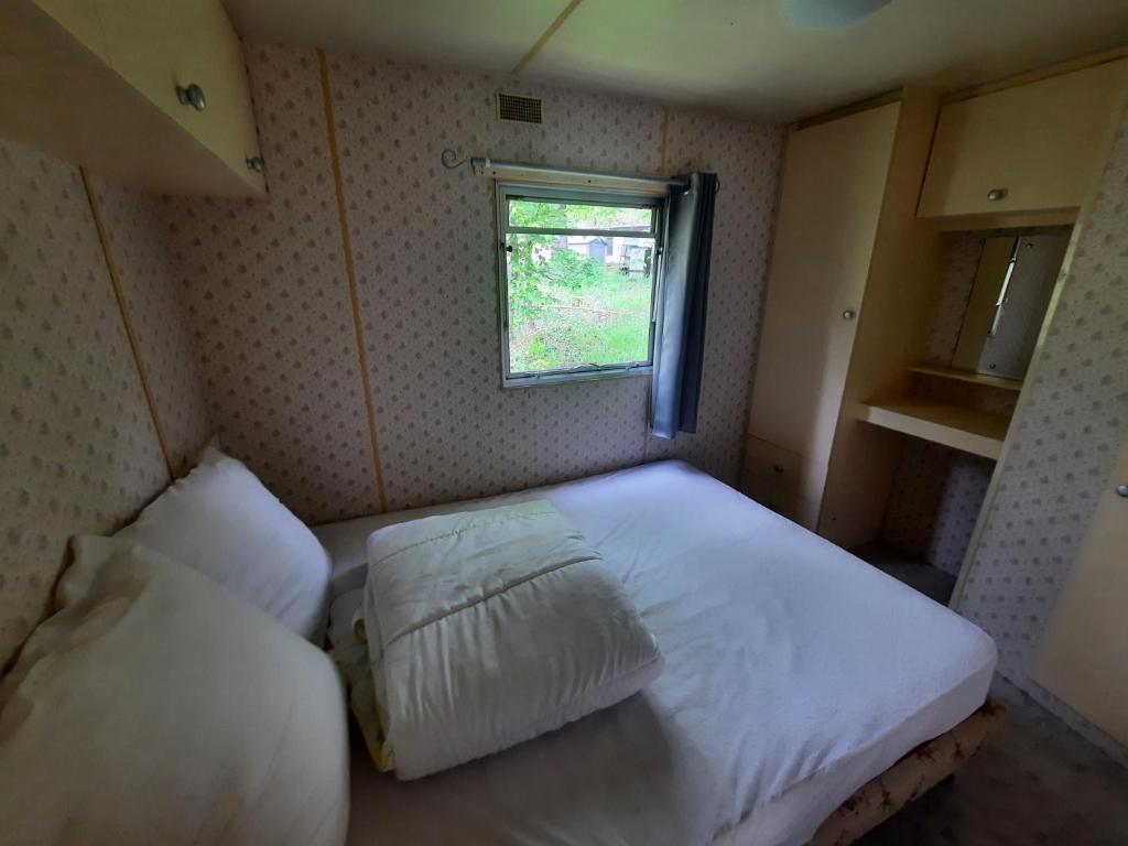 une petite chambre avec un lit et une fenêtre dans l'établissement Mobilhome vintage "Océane", à Tourtoirac