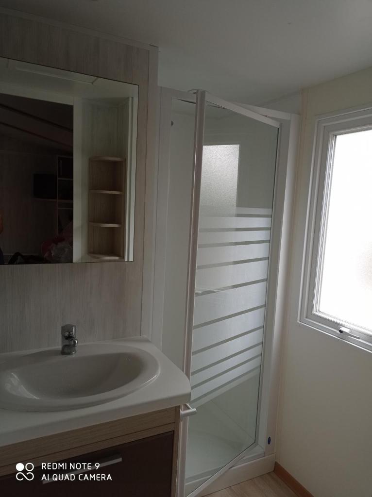 une salle de bain avec un lavabo, un miroir et une fenêtre dans l'établissement Mobil-home, à La Bernerie-en-Retz
