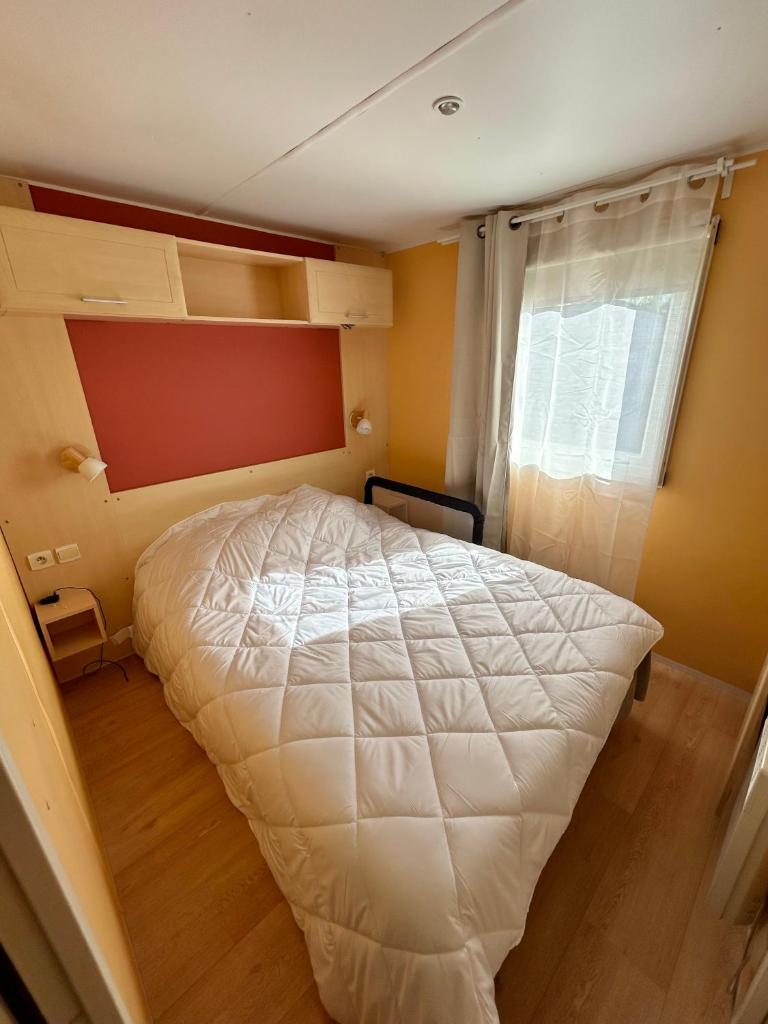 une chambre avec un lit blanc et une fenêtre dans l'établissement Mobil home camping Lalande Mimizan, à Mimizan