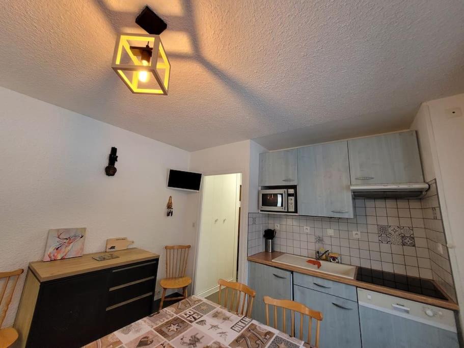 une cuisine avec des armoires bleues et une table avec une lumière dans l'établissement Très bel appartement avec vue, à Thollon-les-Mémises
