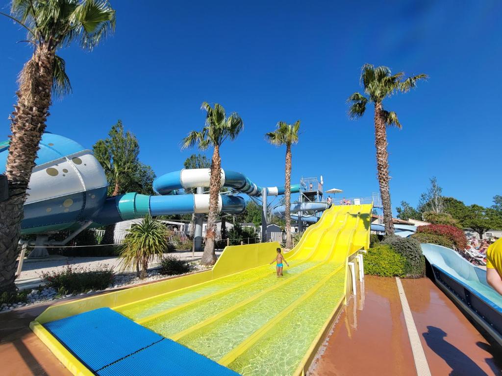 une personne sur un toboggan jaune dans un parc aquatique dans l'établissement Superbe mobile home neuf - Mazet 71 - Camping la Carabasse, à Vias 3 autres photos