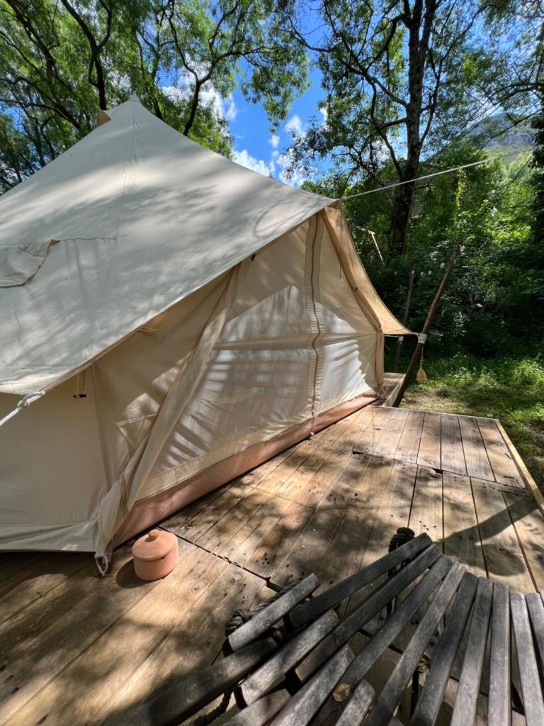 une tente sur une terrasse en bois dans les bois dans l'établissement Tente lodge en pleine nature, à Sumène
