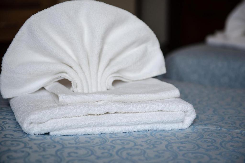 une pile de serviettes posée sur un lit dans l'établissement Albergo Regina Mundi, à Pietra Ligure