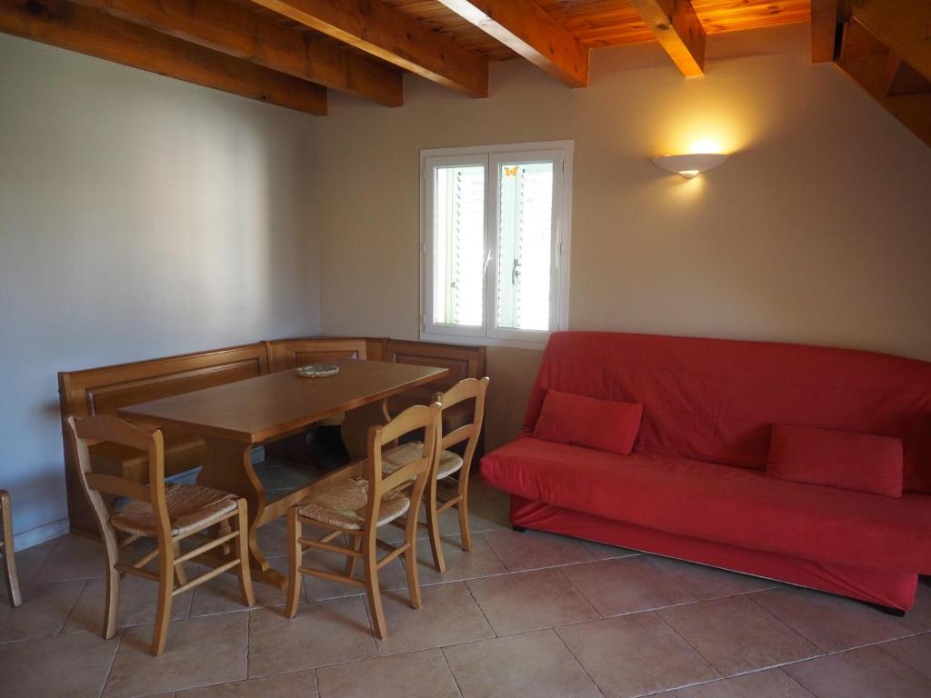 un salon avec une table et un canapé rouge dans l'établissement Gîtes Santa Maria Cap Corse, à Macinaggio