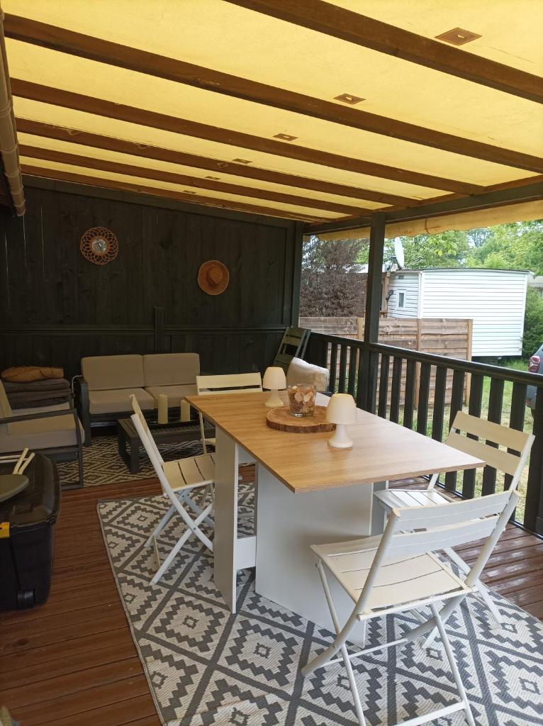 une table et des chaises en bois sur une terrasse avec une table dans l'établissement camping la lande, à Mimizan