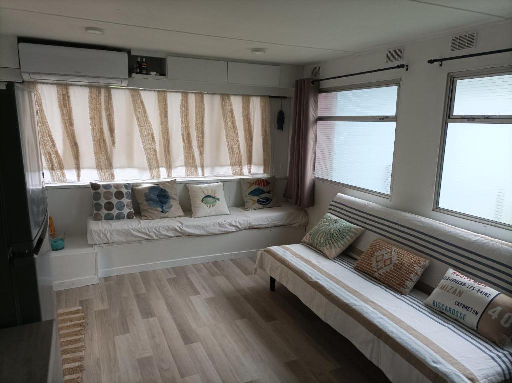un salon avec un canapé et deux fenêtres dans l'établissement camping la lande, à Mimizan