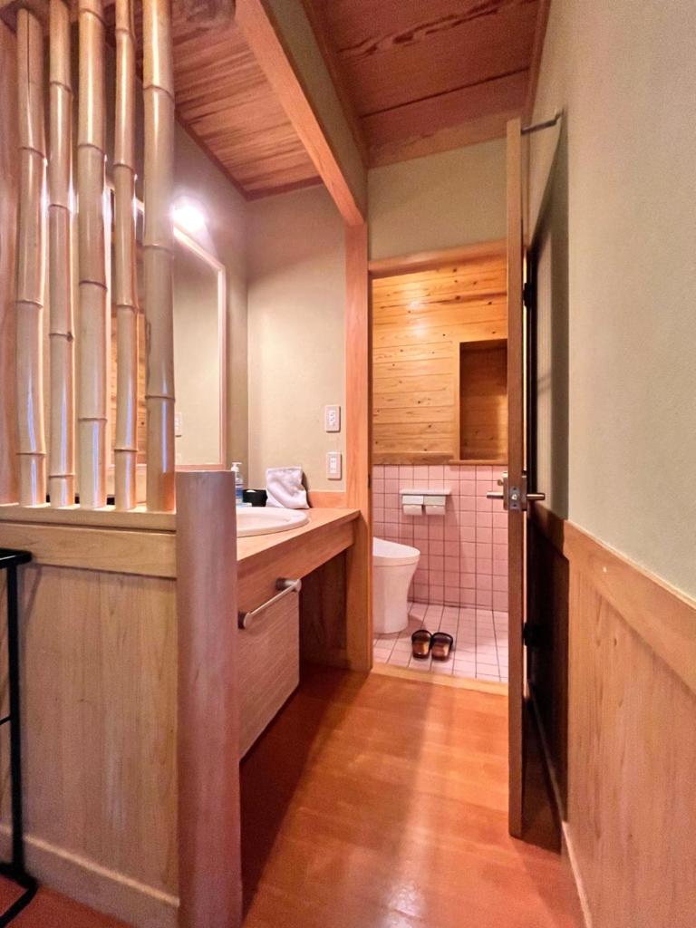 une salle de bain avec un lavabo et des toilettes dans une chambre dans l'établissement Ryokan Kiraku, à Beppu