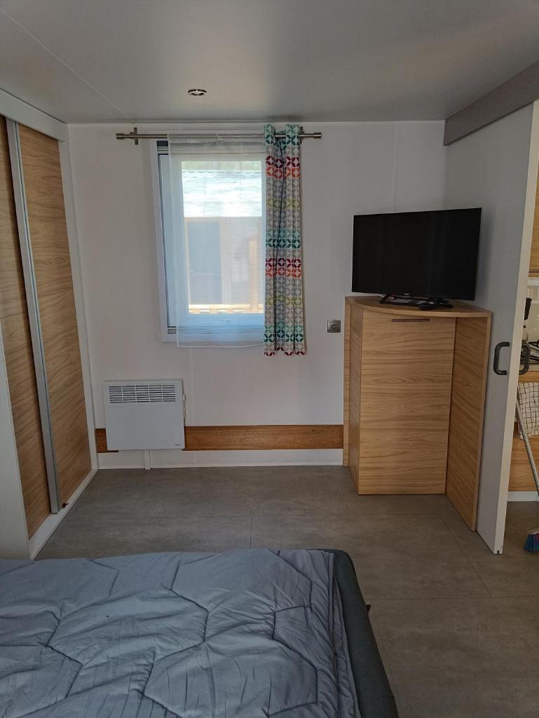 une chambre avec un lit et une télévision à écran plat dans l'établissement Mobil'home PMR sous les pins !, à Seignosse