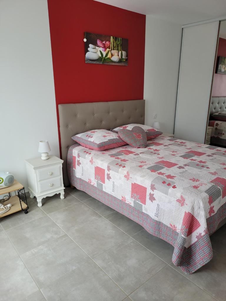- une chambre dotée d'un lit avec un mur rouge dans l'établissement gite de la Terriere en Dordogne-Perigord, à La Chapelle-Aubareil
