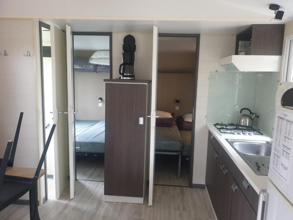 Il comprend une petite cuisine avec un évier et une chambre avec un lit. dans l'établissement Mobilhome proche Puy duFou, à La Boissière-de-Montaigu